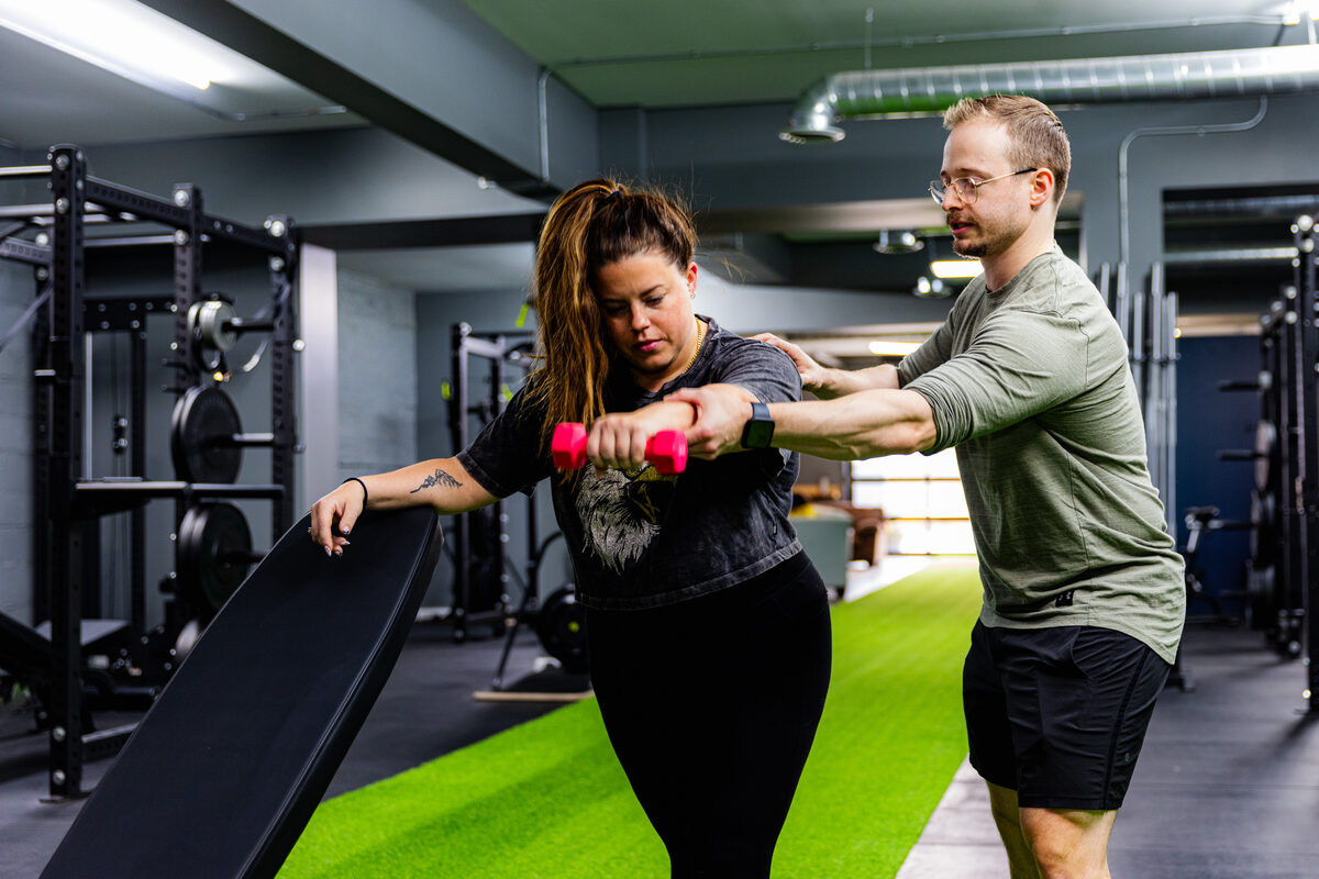 A personal trainer coaching a member through a strength exercise